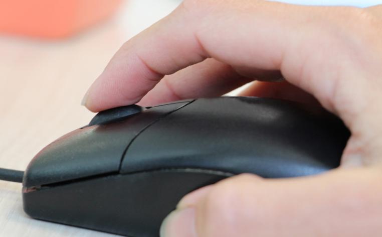Main posée sur une souris informatique